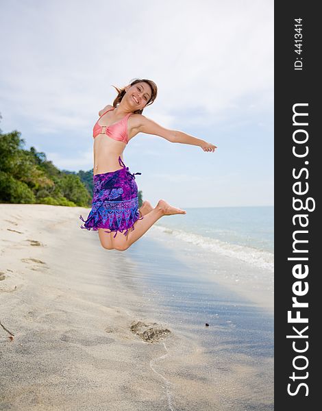 Young woman jumping happilly at the beach. Young woman jumping happilly at the beach