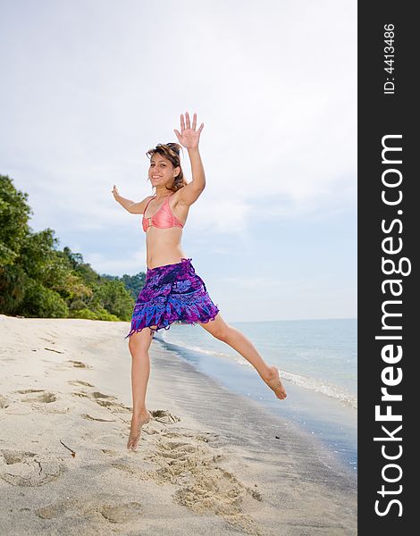 Young woman jumping happilly at the beach. Young woman jumping happilly at the beach