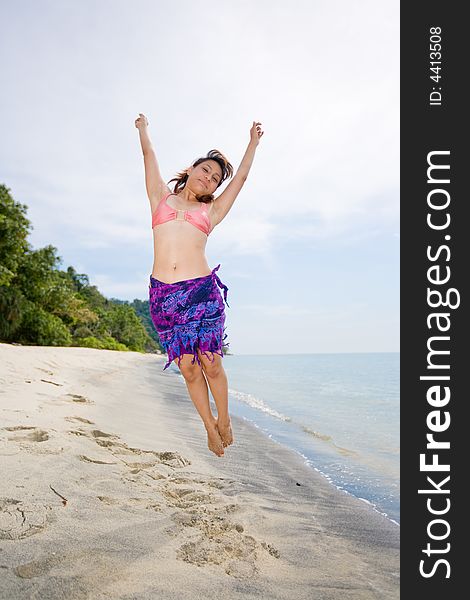 Young woman jumping happily at the beach. Young woman jumping happily at the beach