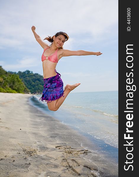 Young woman jumping happily at the beach. Young woman jumping happily at the beach