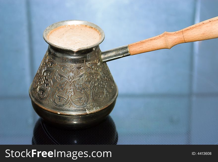 Turkish coffee pot with coffee on a stove. Close-up.