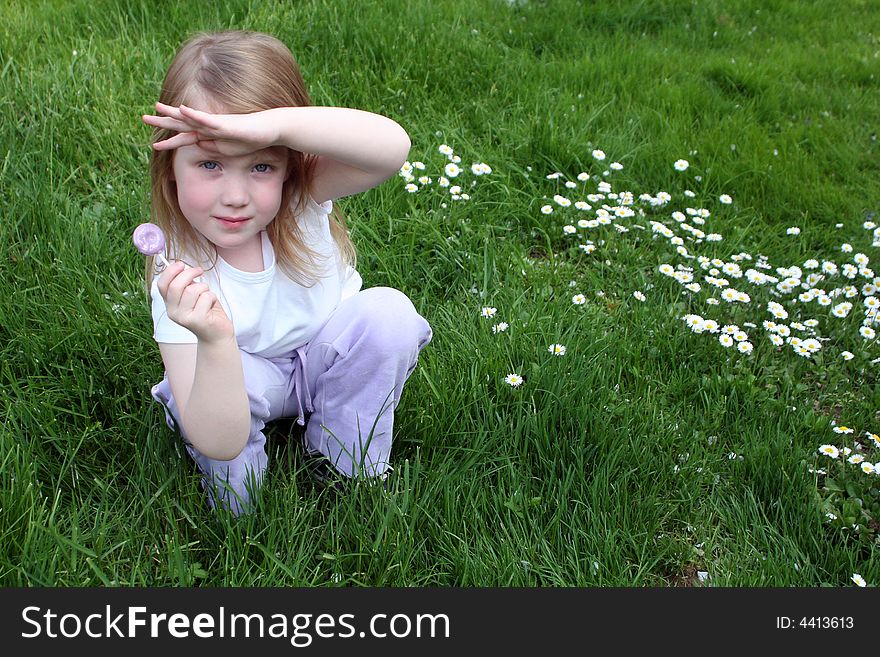 A young girl holding a lollipop in the daisy field
