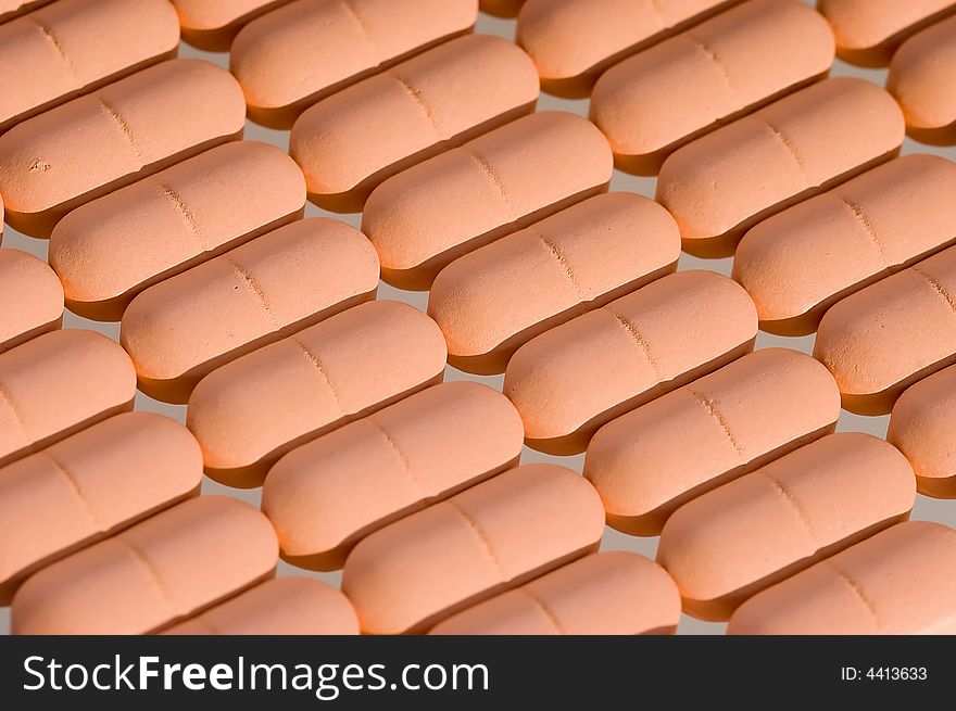 Rows of pink pills over white