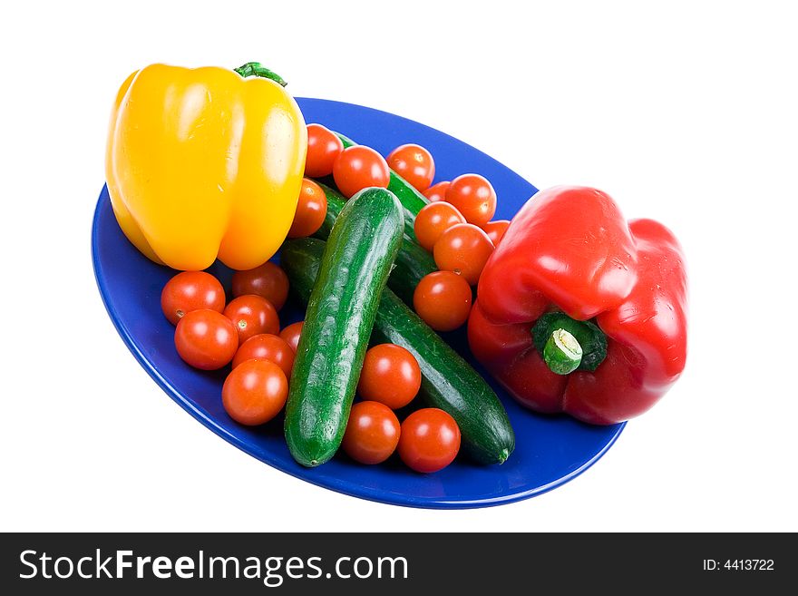 Set of vegetables on a dark blue plate isolated on a white background