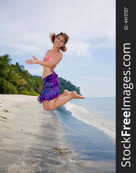 Young woman jumping happily at the beach. Young woman jumping happily at the beach