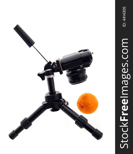 Photographing of orange. Black tripod and camera isolated on white