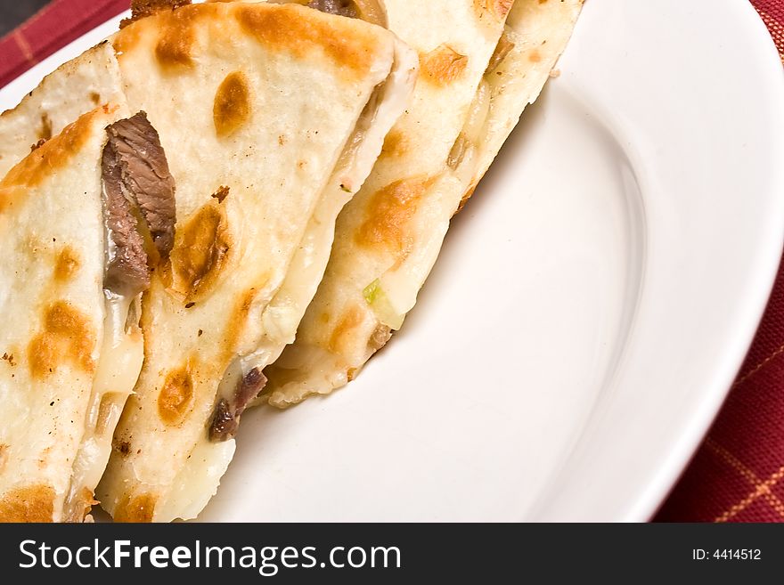 Fresh off the stove a steak Quesadilla on a white plate