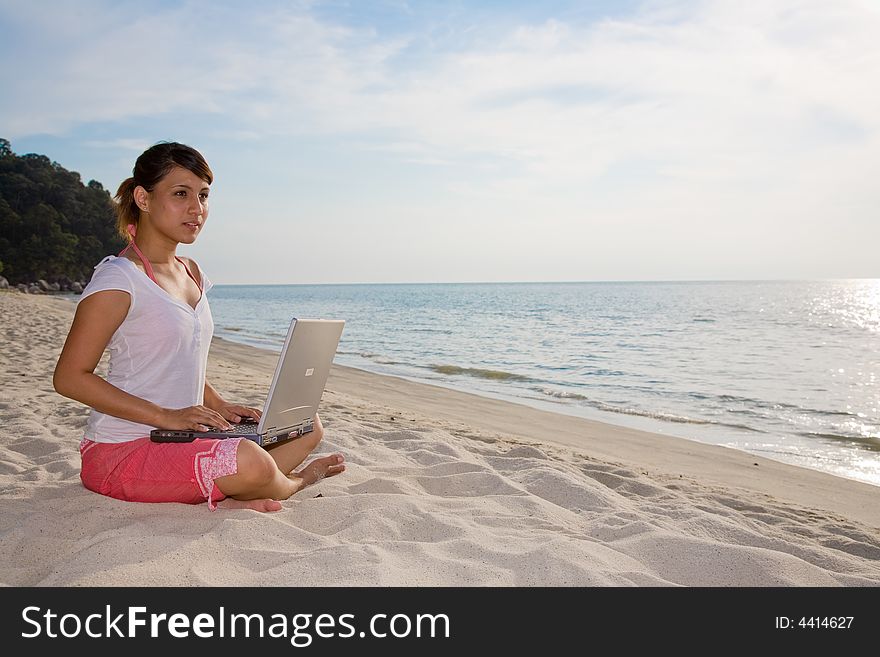 Woman working on her laptop  on a beautiful beach. Woman working on her laptop  on a beautiful beach