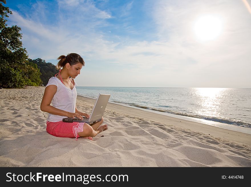 Woman working on her laptop on a beautiful beach. Woman working on her laptop on a beautiful beach