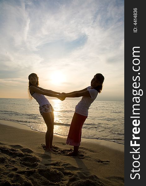 Two young woman relaxing at the beach during sunset. Two young woman relaxing at the beach during sunset