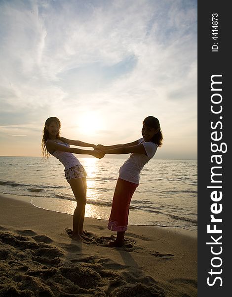 Two young woman relaxing at the beach during sunset. Two young woman relaxing at the beach during sunset