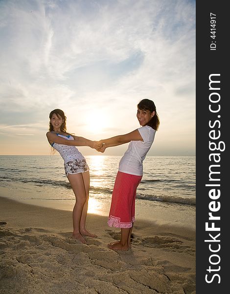 Two young woman relaxing at the beach during sunset. Two young woman relaxing at the beach during sunset