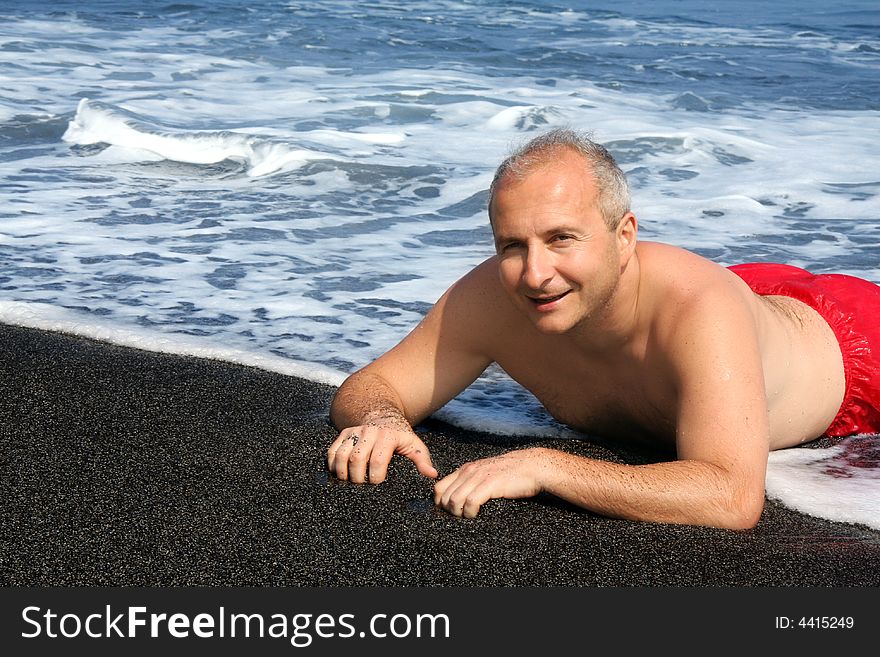 Mature man on a black sand beach on Big Island, Hawaii