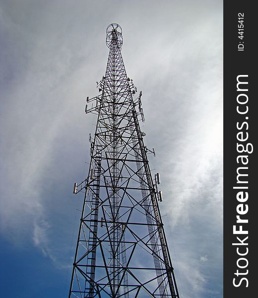 This is a transmitting and receiving tower against a whispy cloud type blue sky. This is a transmitting and receiving tower against a whispy cloud type blue sky