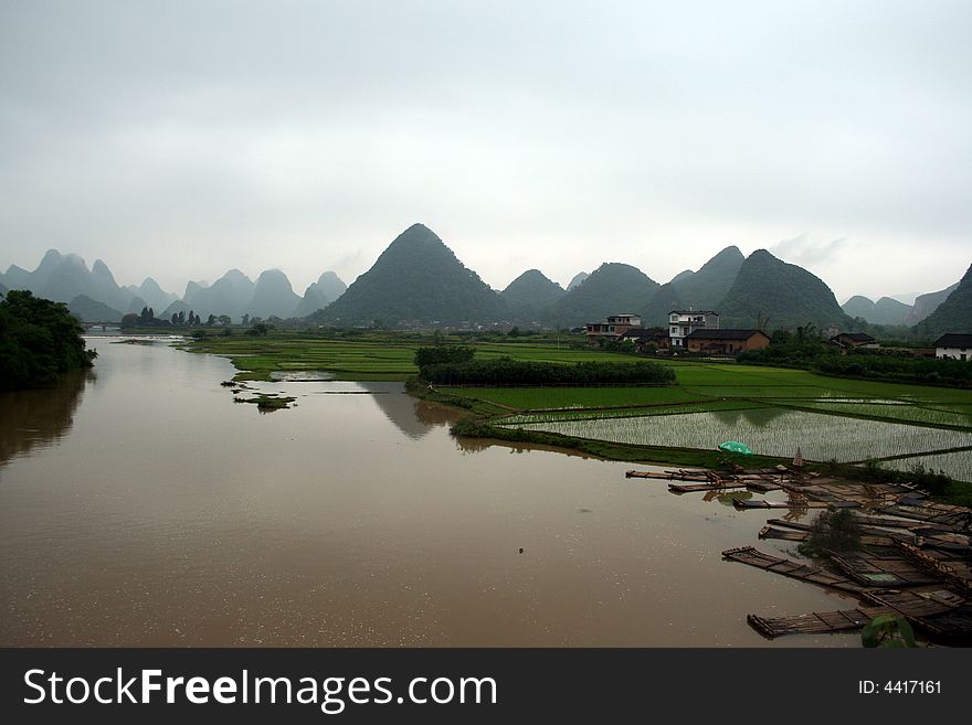 A small waterfront, Bamboo raft on the river through the paddy and hills of Guilin. . A small waterfront, Bamboo raft on the river through the paddy and hills of Guilin.