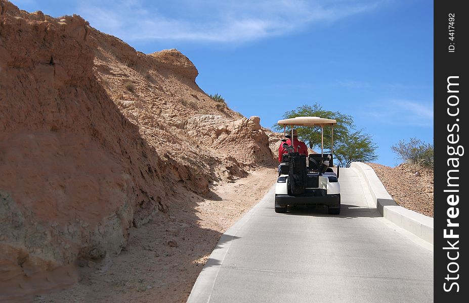 Man driving golf cart on desert course