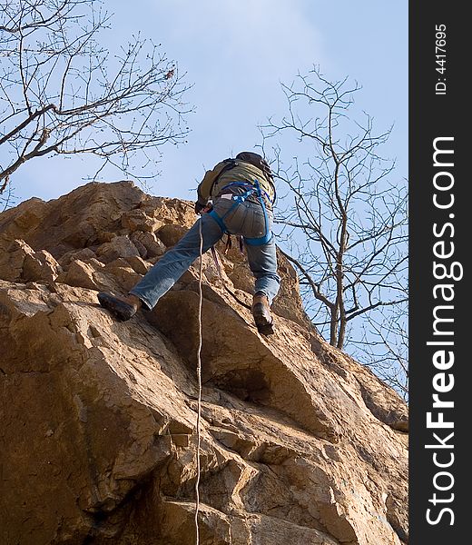 Climber hanging on the rope on the rock against blue sky. Climber hanging on the rope on the rock against blue sky