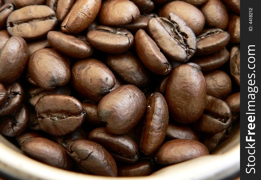 Close up of whole roasted coffee beans in a grinder