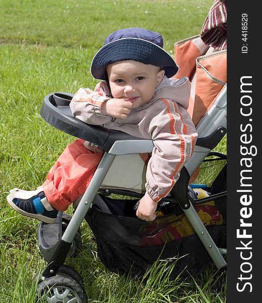 Kid walking in the stroller on the spring green meadow. Kid walking in the stroller on the spring green meadow