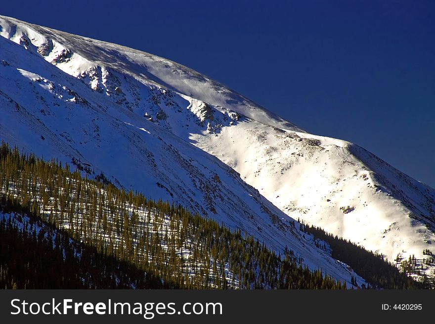 The snow covered peaks of Colorado's Rocky Mountains along Berthoud Pass bathe in the morning sunlight. The snow covered peaks of Colorado's Rocky Mountains along Berthoud Pass bathe in the morning sunlight