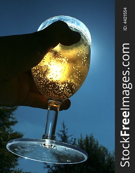 A person holding a glass of drink illuminated by the sun. A person holding a glass of drink illuminated by the sun