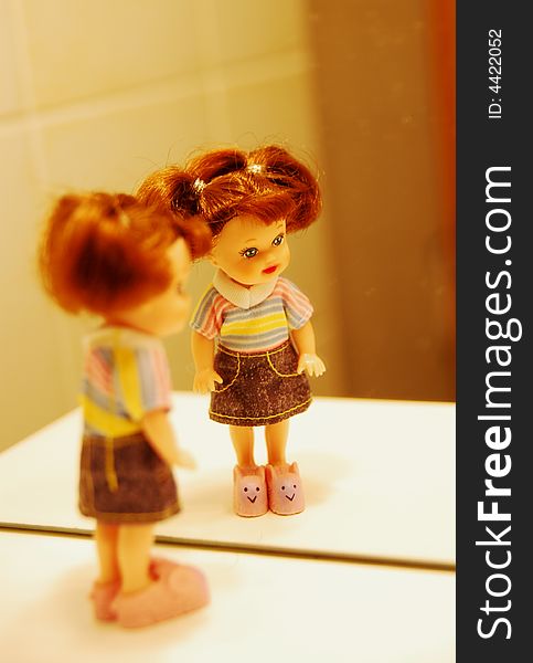 A doll in front of a mirror, with colorful Tshirt and jeans skirt