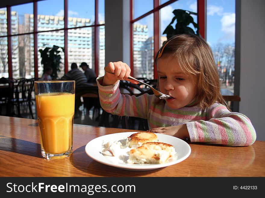 Girl eating cheese cake with a fork at a restaurant