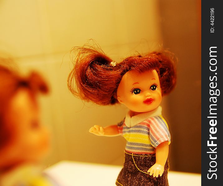 A doll in front of a mirror, with colorful Tshirt and jeans skirt