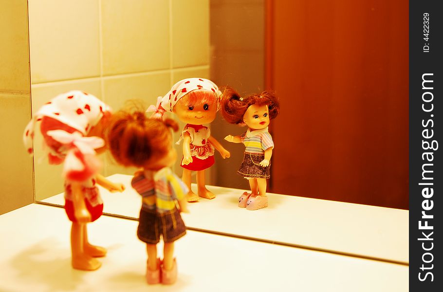 2 dolls in front of a mirror, with colorful clothers