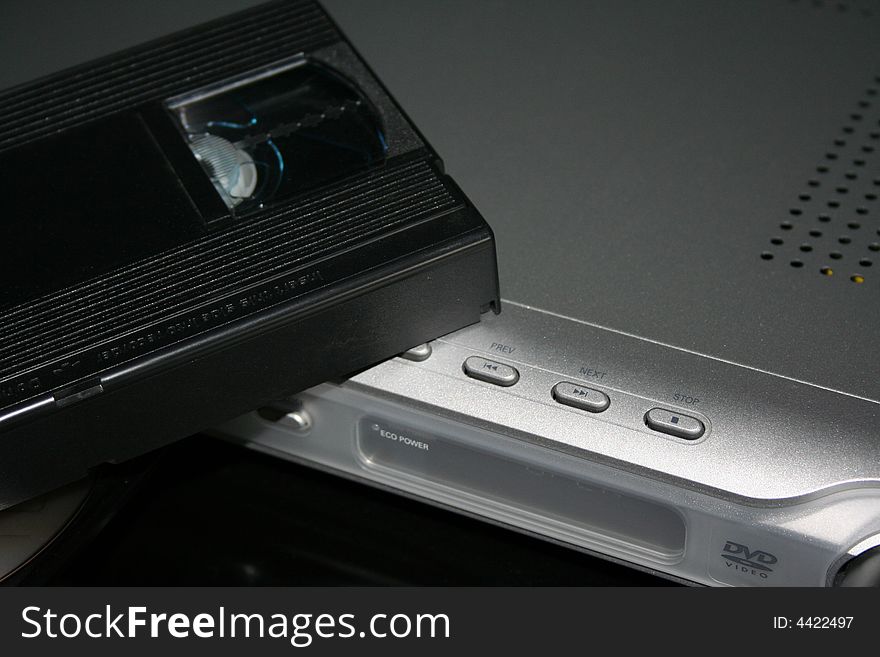 It's an old vhs, lying down on a silver modern dvd player. It's an old vhs, lying down on a silver modern dvd player.
