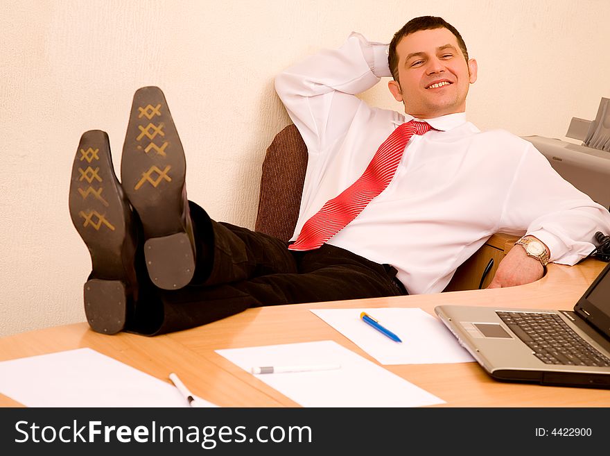 Young businessman relaxing at office with legs on table. Young businessman relaxing at office with legs on table