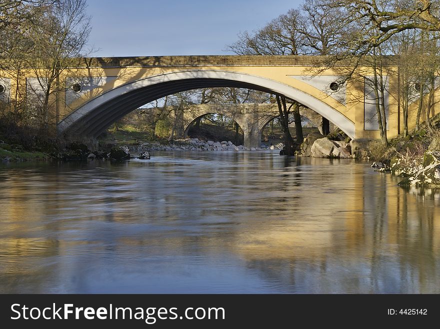 The medieval Devils bridge seen through the modern road gridge on the river Lune near Kirkby Lonsdale, Cumbria, UK. The medieval Devils bridge seen through the modern road gridge on the river Lune near Kirkby Lonsdale, Cumbria, UK