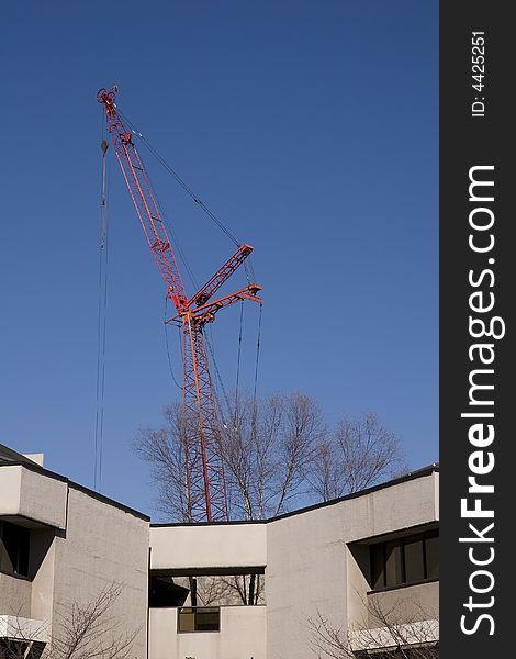 A red construction crane over a completed building. A red construction crane over a completed building