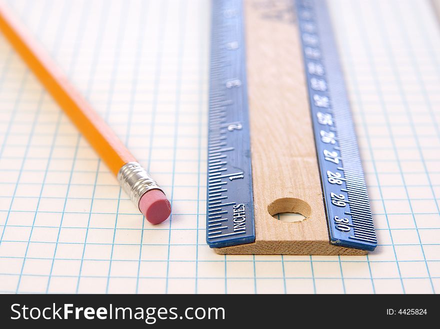 Wooden ruler and pencil on graph paper. Low depth