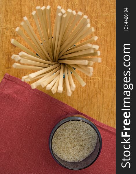 Chopsticks and rice in the glasses on wood and textile background