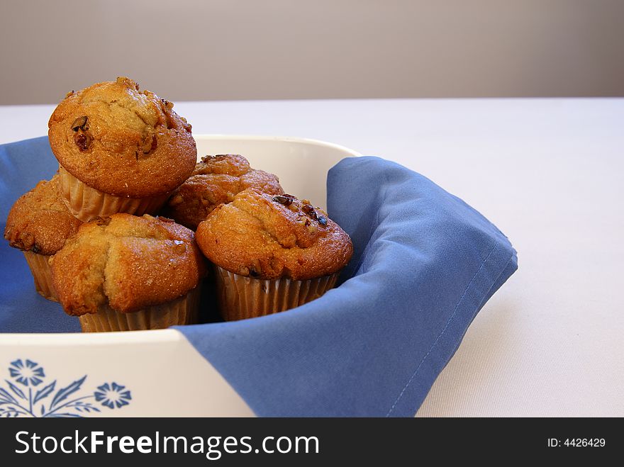 Banana Nut Muffins stacked in white crock with blue napkin