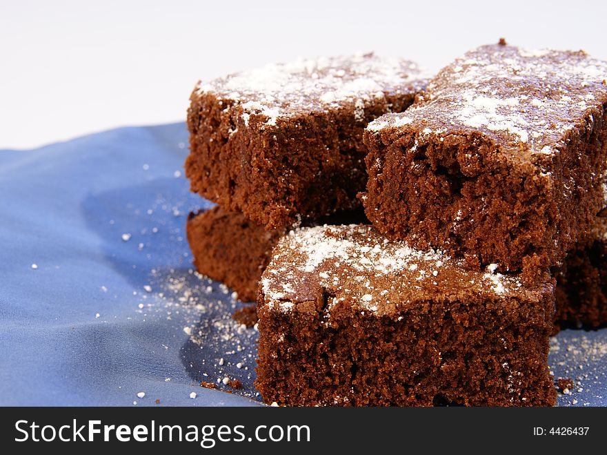 Thick chocolate fudge brownies with powdered sugar sprinkled on top.