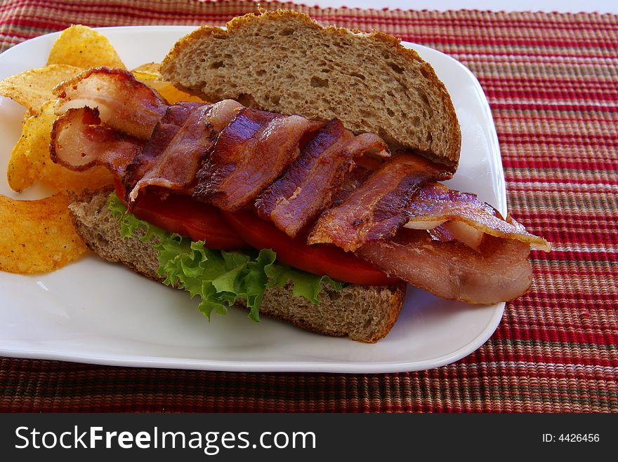 Bacon, Lettuce, and Tomato (BLT) on rustic whole grain loaf bread with chips. Bacon, Lettuce, and Tomato (BLT) on rustic whole grain loaf bread with chips.