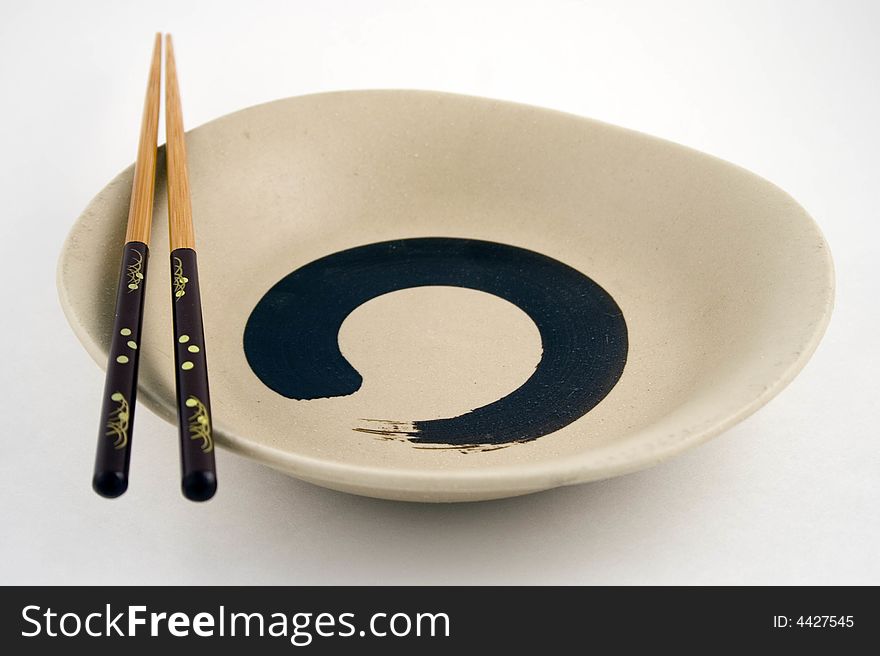 Black Chopsticks placed on Plate over white background