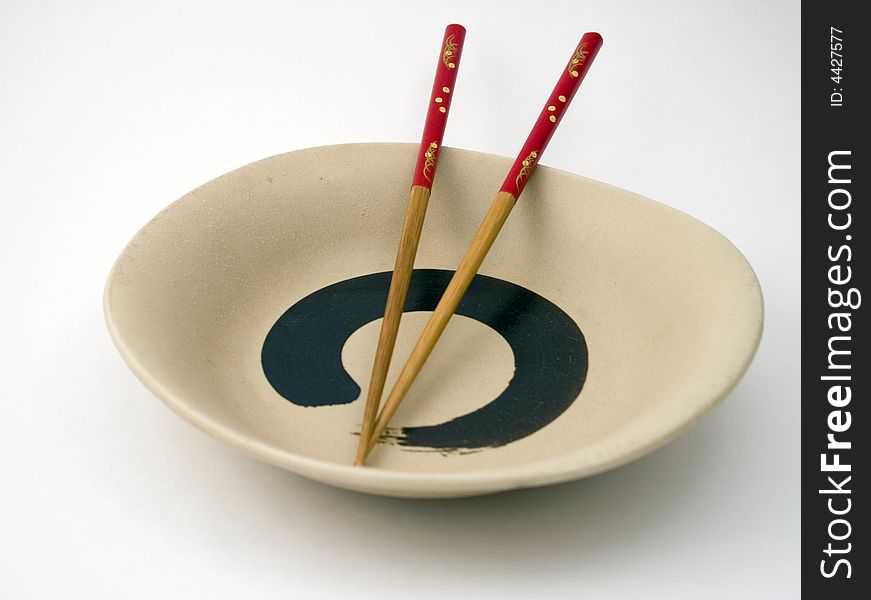 Red Chopsticks placed on Plate on white background