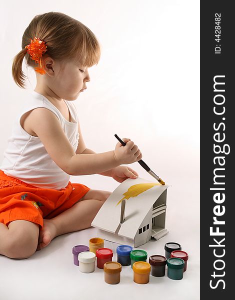 Home Improvement - Little Girl repairs. Child colors by paint the mock-up of the house
