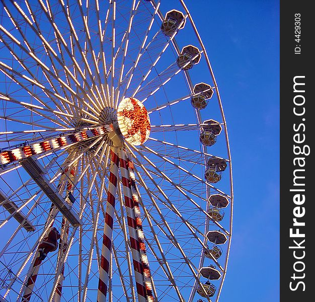 Ferris wheel with lights around against a blue sky