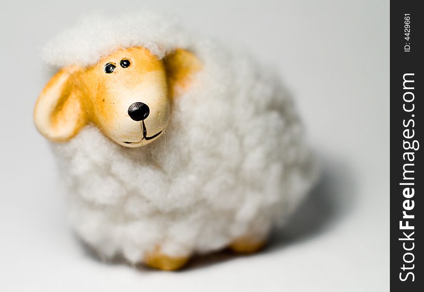 White and yellow sheep toy on grey background. White and yellow sheep toy on grey background