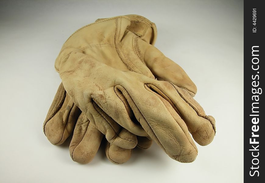 Front view of worn leather work gloves against a neutral background