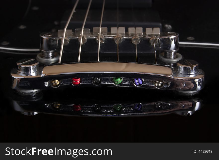 Guitar bridge with reflection on black guitar