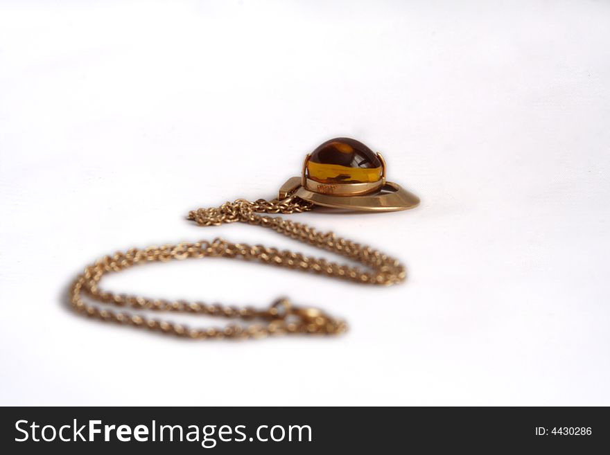 Precious gold(en) pendant with stone from amber lies