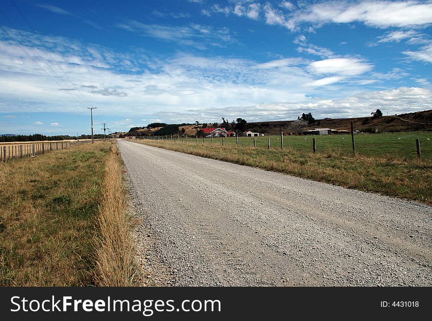 A rural roadway in the New Zealand countryside with a sheep farm/ranch in background. A rural roadway in the New Zealand countryside with a sheep farm/ranch in background
