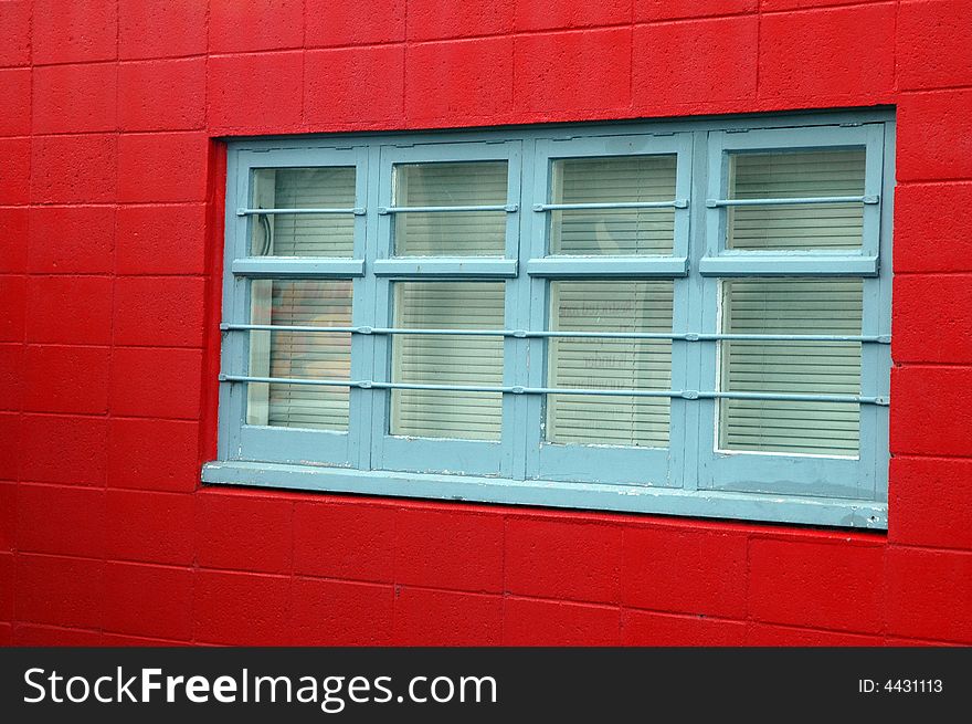 Blue wooden window frame against a red painted brick exterior. Blue wooden window frame against a red painted brick exterior