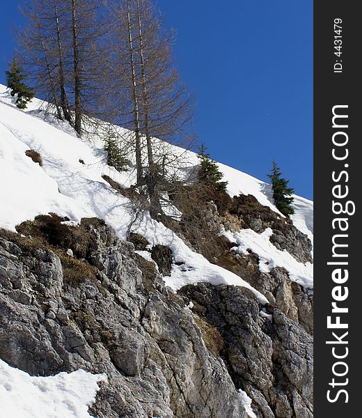 Snowy mountain slope, rocks and fresh snow, clear blue sky background. Snowy mountain slope, rocks and fresh snow, clear blue sky background