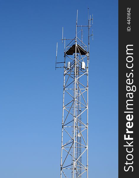Highest part of a radio antenna with blue sky in the background.